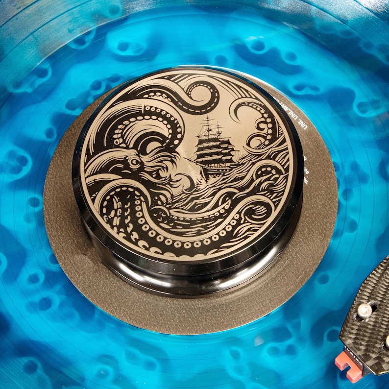 The Kraken engraved aluminum record weight featuring a sea monster and sailing ship on blue vinyl